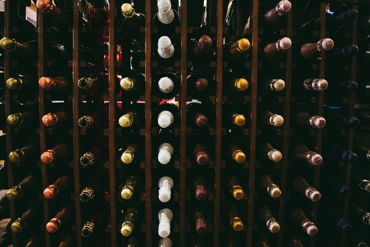 Casier de cave rempli de bouteilles couchées, cols alignés, rouges et blancs mélangés