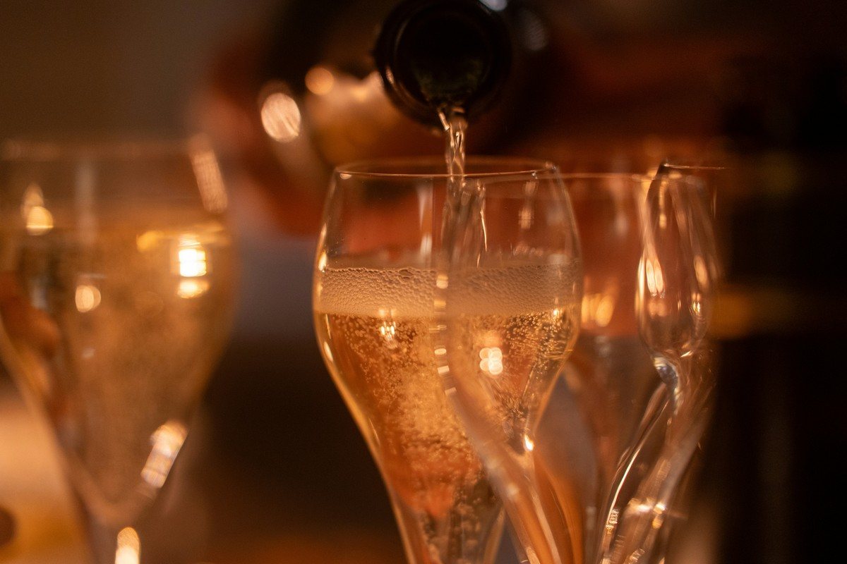 Champagne versé dans une flûte à l'apéritif, bulles fines et lumière chaude en début de repas