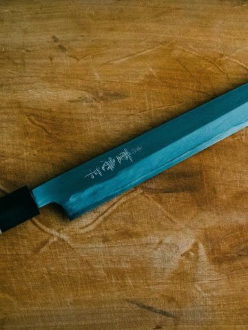 Couteau de cuisine japonais de type yanagiba posé sur une planche en bois