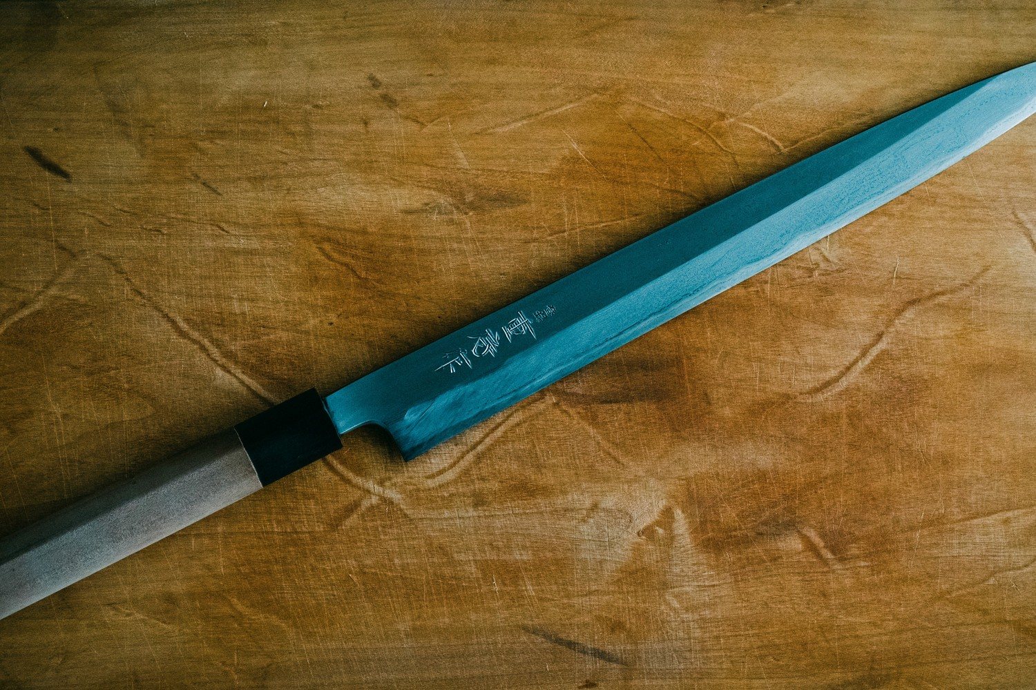 Couteau de cuisine japonais de type yanagiba posé sur une planche en bois
