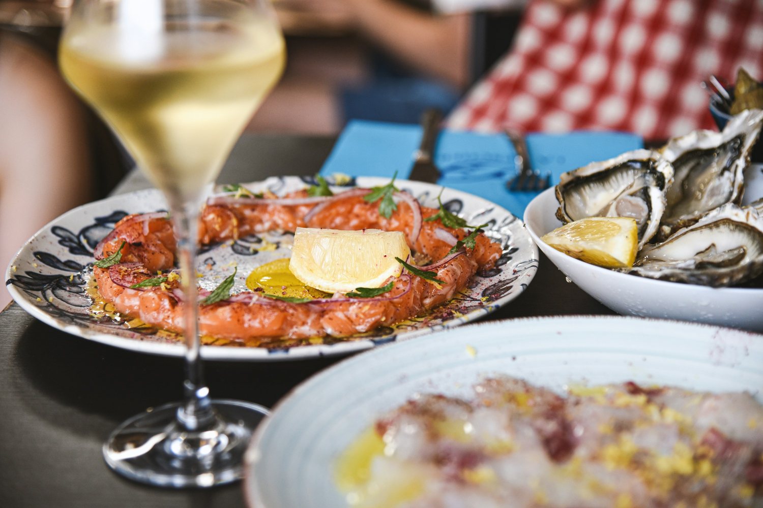 Verre de vin blanc servi devant une assiette de crevettes et une coupelle d'huîtres sur une table de bistrot